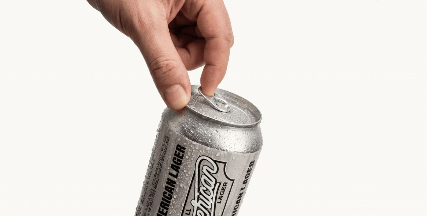 A hand opening a chilled can of All American Lager
