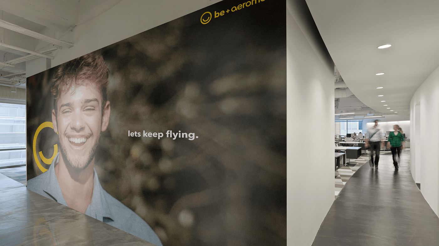A Be wall mural with a smiling portrait in an office corridor