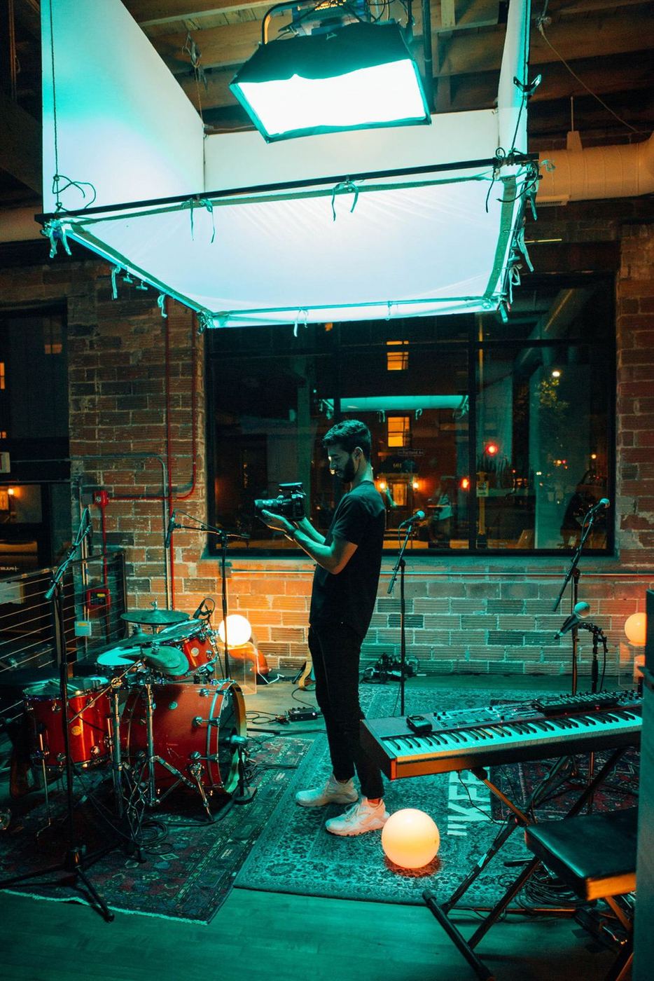 Camera operator filming under a soft box in a brick-walled studio