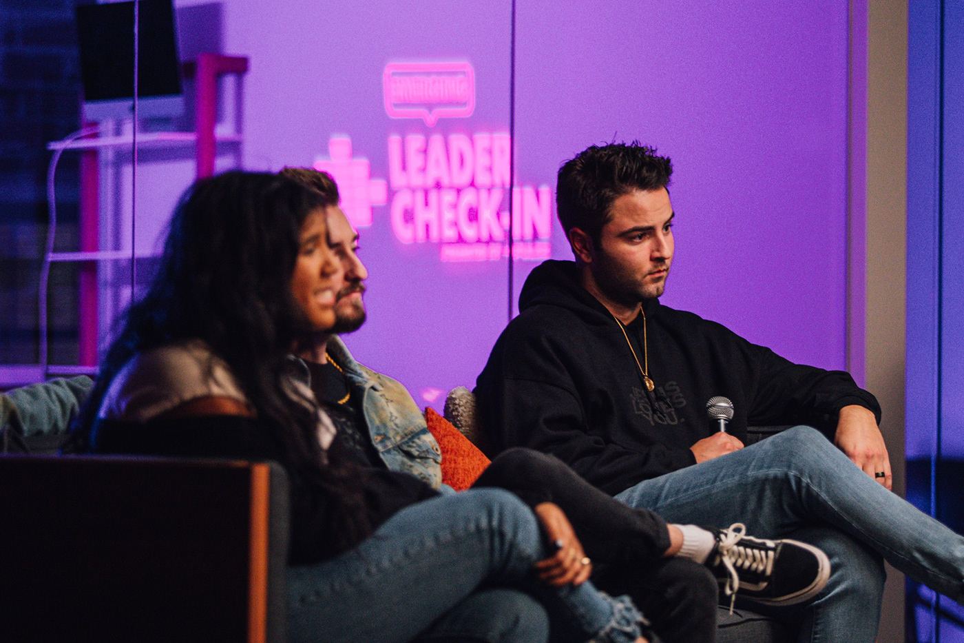 Two guests on a sofa under the purple Leader Check-In projection