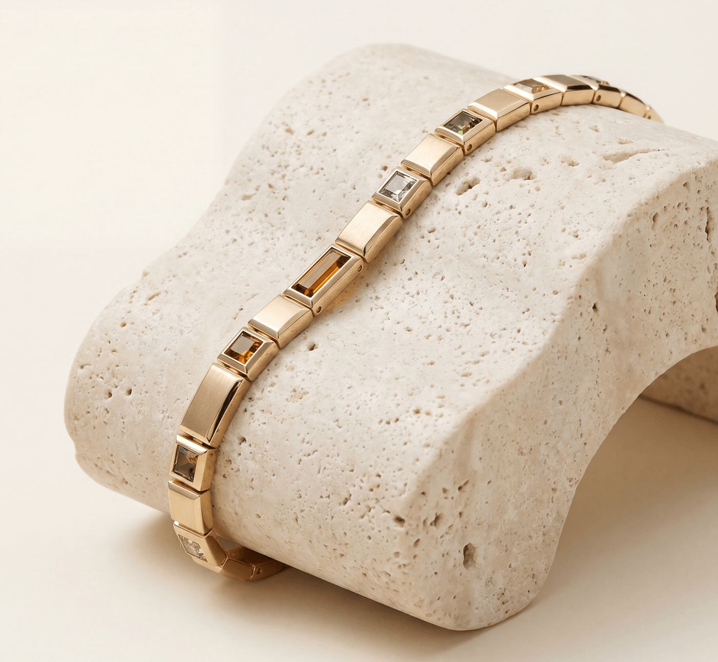 A gold-toned EyeMatch bracelet resting on a sculpted stone
