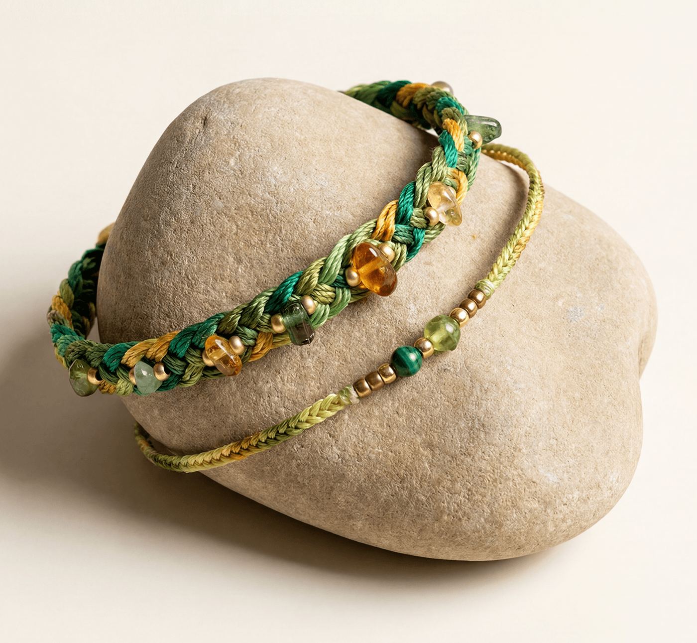A green and amber woven bracelet wrapped around a stone