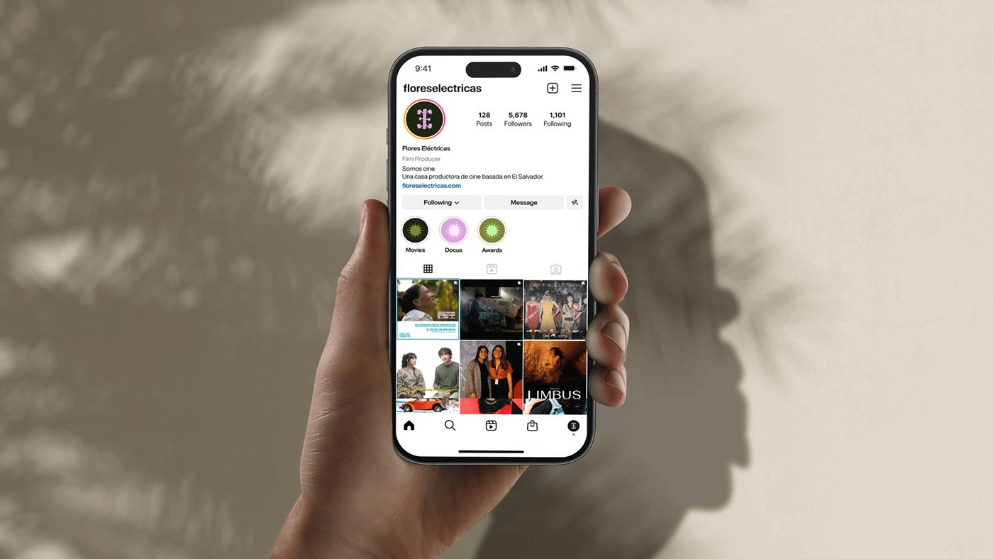 The Instagram profile on a phone held against a sand wall