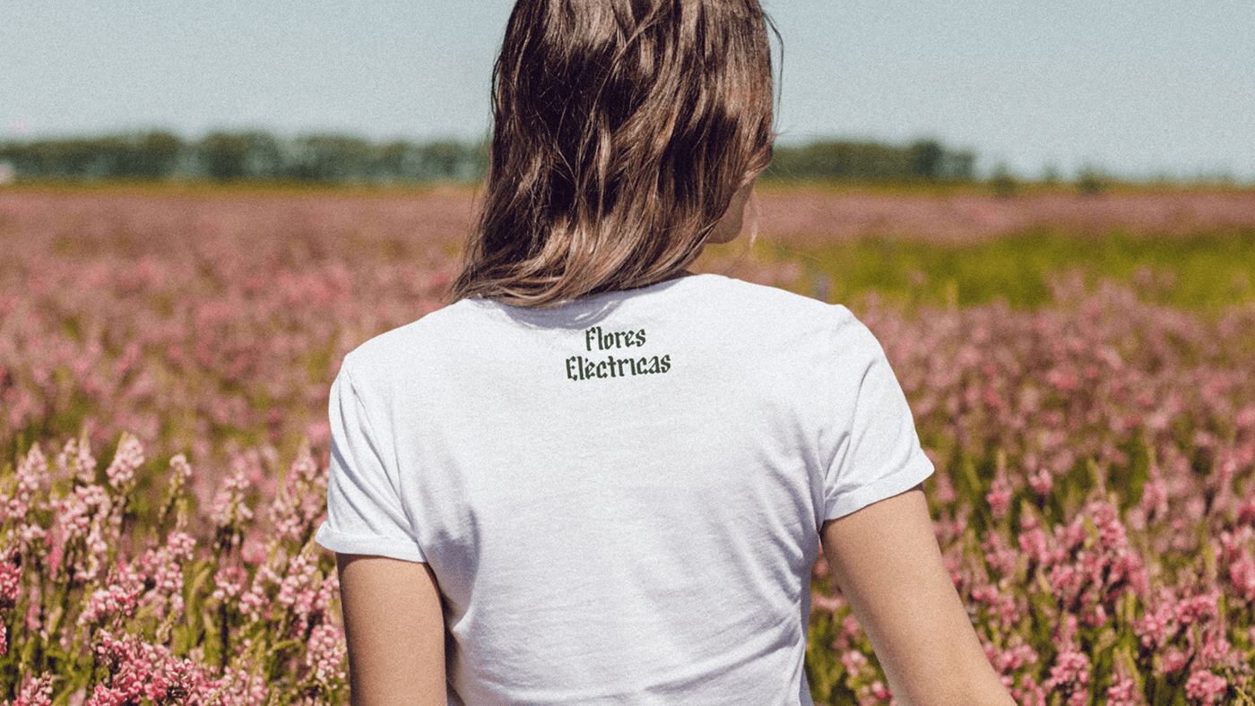 Back of a white tee with the Flores Eléctricas logotype, in a flower field