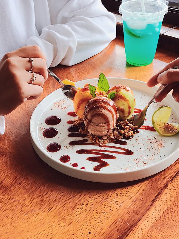 A plated ice-cream dish with sauce and lime, shared at a wooden table