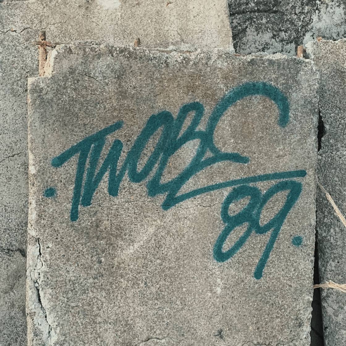 A green spray-painted tag on a concrete block
