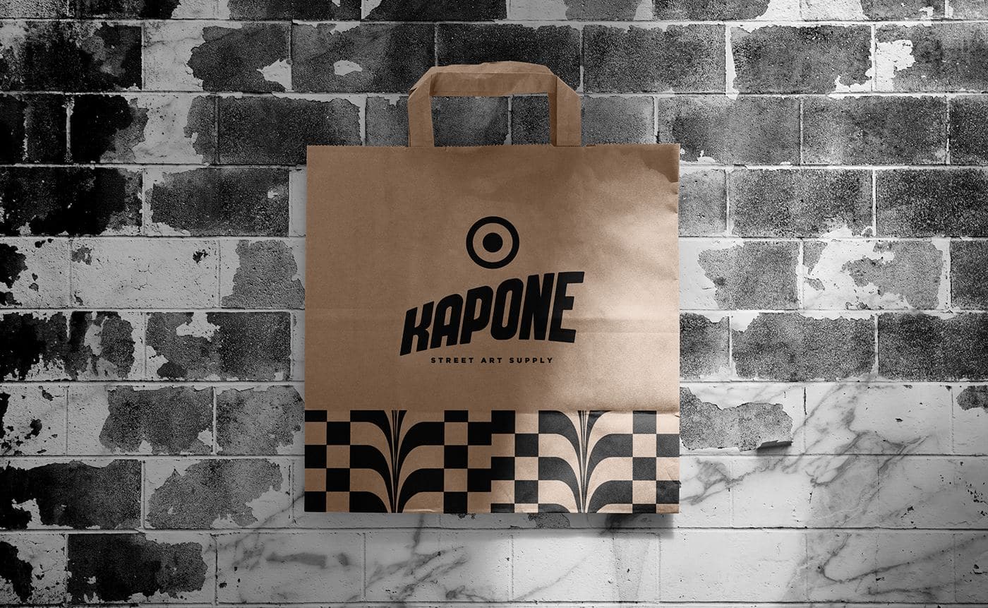 A kraft-paper Kapone shopping bag against a whitewashed brick wall