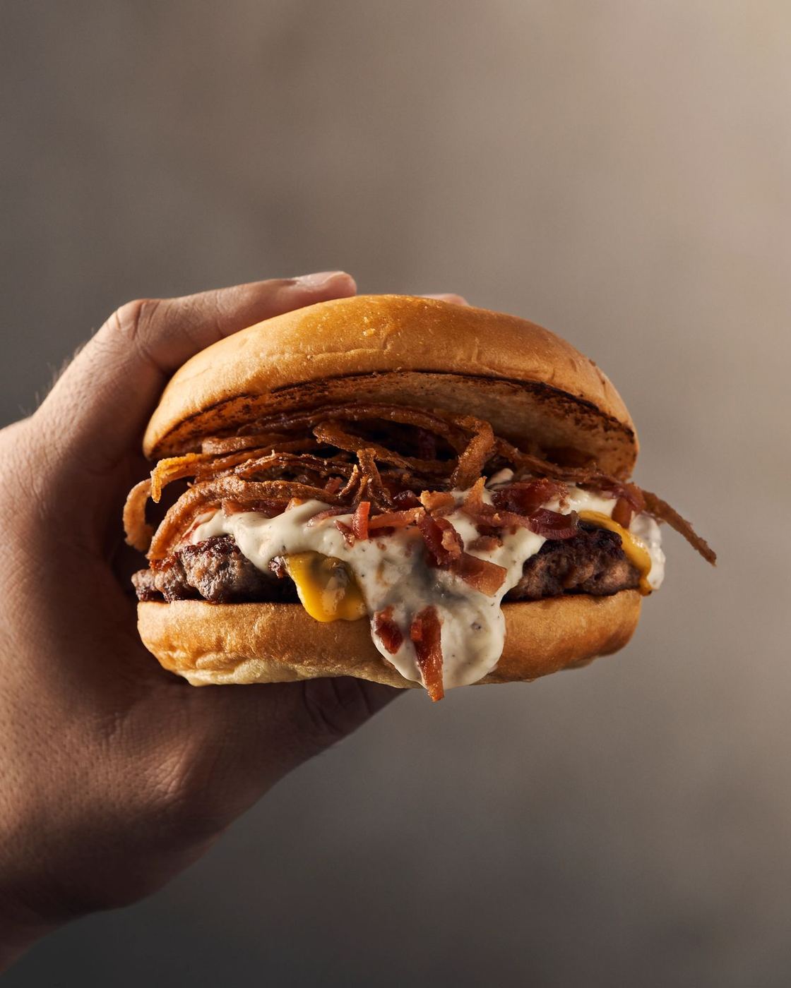 La Diosa burger held up in one hand, close up