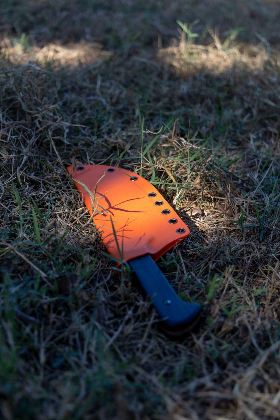 MAXSA blade in its orange sheath lying in the grass