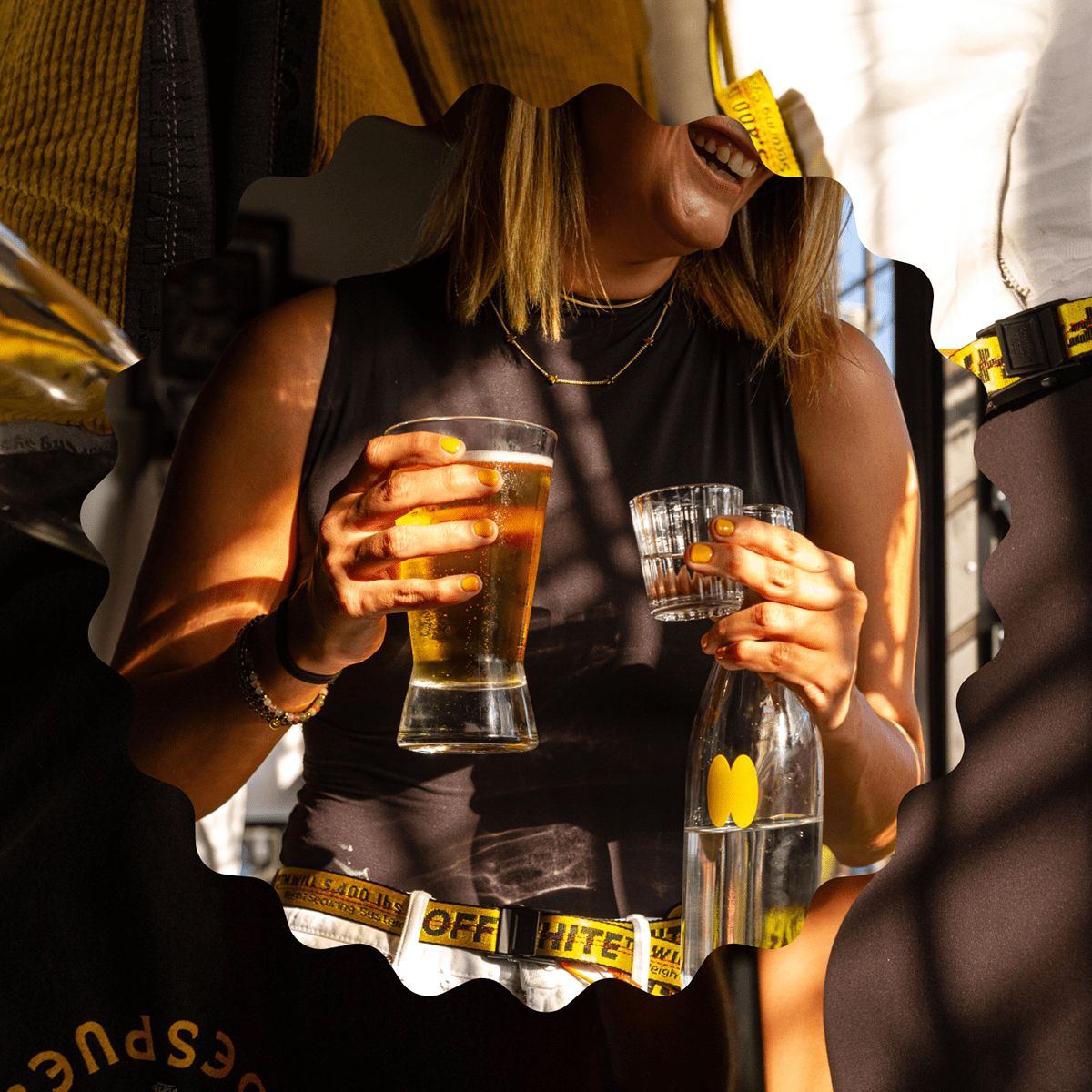 A woman holding a beer and a mezcal glass, framed by a wavy cut-out
