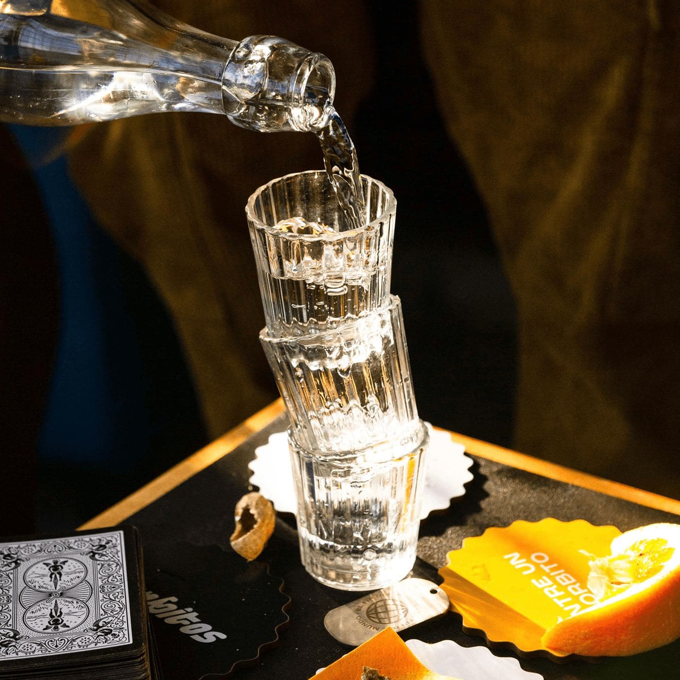 Mezcal poured into a stack of glasses on a Sorbitos coaster